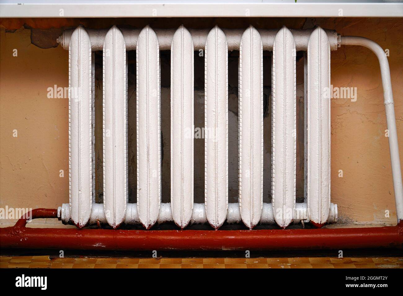 Vecchio radiatore in ghisa sullo sfondo della parete grigia. Riscaldamento della batteria Foto Stock