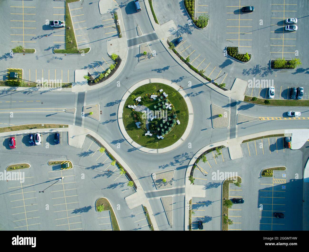 Vista aerea diretta di una rotatoria a 4 vie nel centro della città, tutti i lati circondati da parcheggi leggermente riempiti. Foto Stock