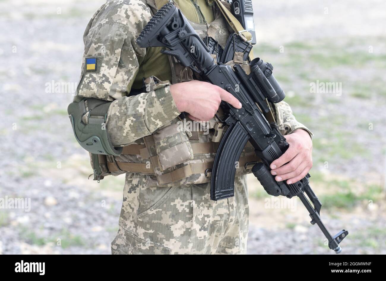 Soldato dell'Ucraina con fucile d'assalto e bandiera dell'Ucraina su uniforme militare. Soldato ucraino con fucile d'assalto AK. Foto Stock