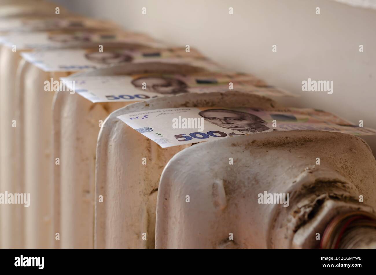 Migliorare l'efficienza del sistema di riscaldamento e il concetto di risparmio energetico. Denaro che si trova sopra una vecchia batteria di riscaldamento in ghisa. Ucraino cinque Foto Stock