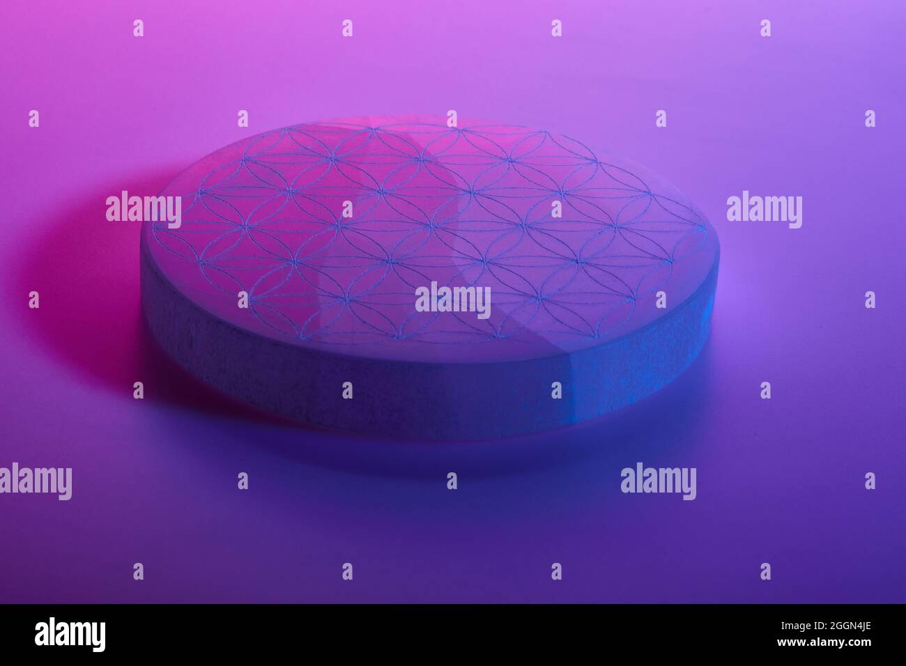 Pietra rotonda con intaglio sotto luci al neon blu viola e rosse Foto Stock