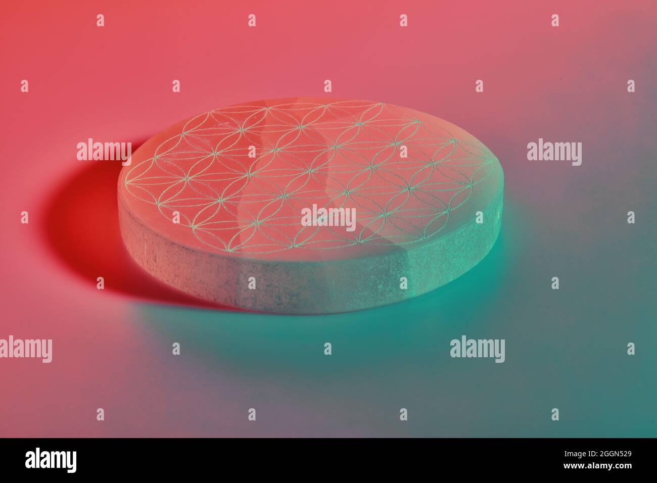 Pietra rotonda con intaglio sotto luci al neon blu viola e rosse Foto Stock