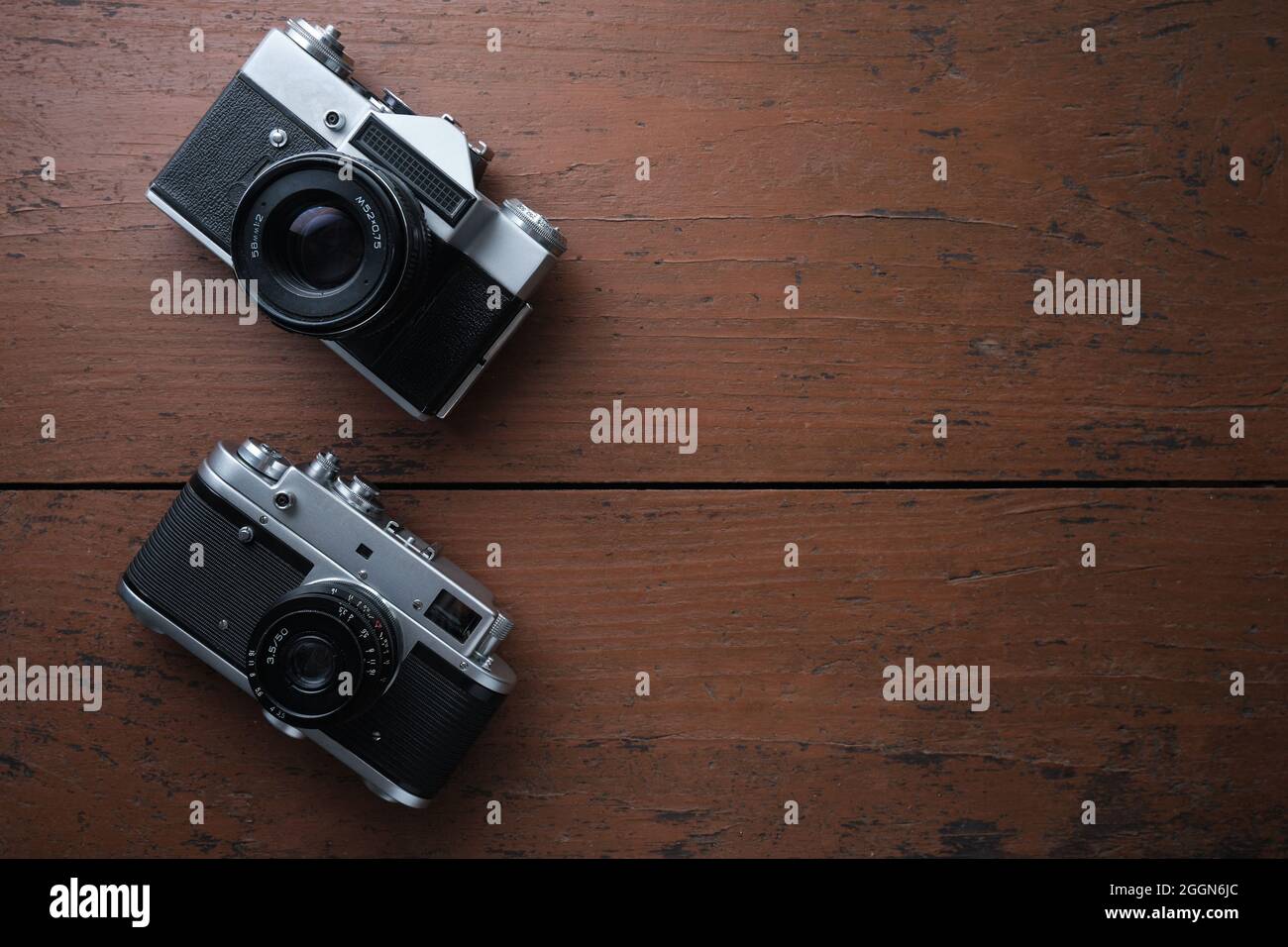 Vecchia telecamera a film metallico vintage da 35 mm, primo piano. Spazio per il testo. Vista dall'alto. La superficie ruvida in legno è di colore marrone. Foto Stock