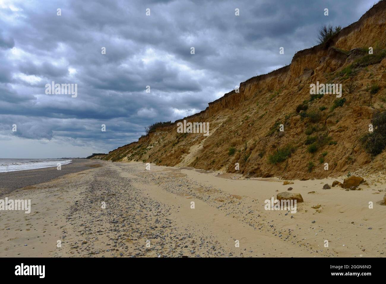 Vista lungo la riva a Cove Hythe con la scogliera di sabbia erodente e le scure nuvole tempestose. Foto Stock