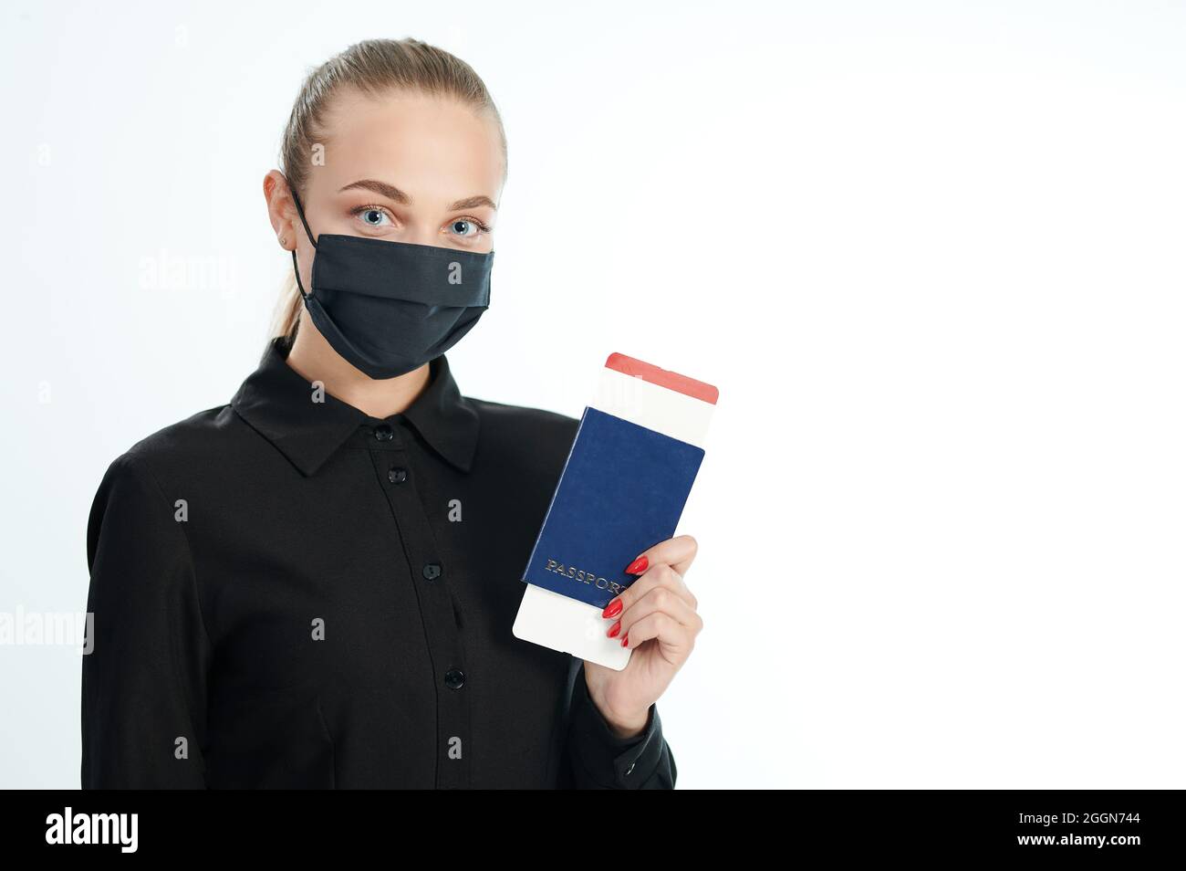 Donna in maschera con biglietto di volo in passaporto in mano isolato su sfondo bianco studio Foto Stock