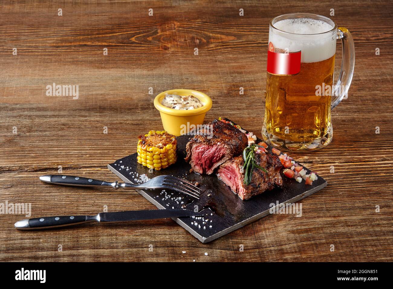 Filetto alla griglia roastbeef bistecca e salsa di funghi su nero tagliere  e bicchiere di birra su sfondo di legno Foto stock - Alamy
