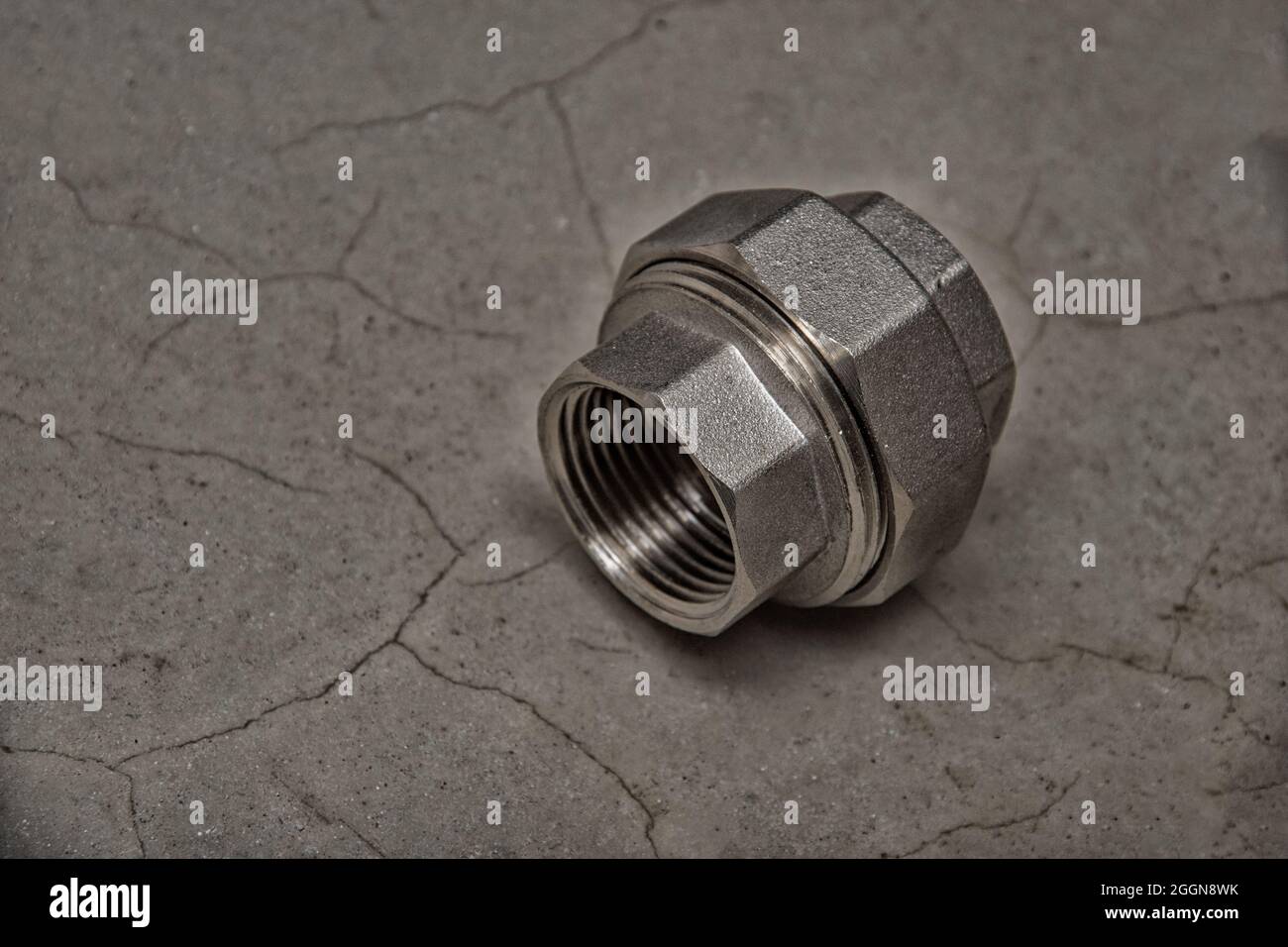 Giunto riduttore in ottone. Raccordo per tubi con filettatura femmina su sfondo di cemento grigio scuro, primo piano, spazio di copia. Collegamento dei tubi. Concetto di rinnovamento Foto Stock