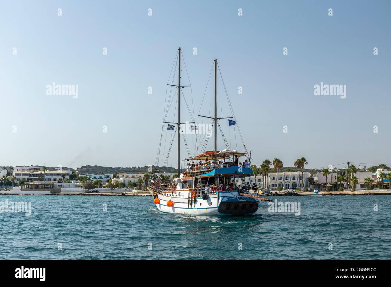 Una gita in barca che lascia il porto di Mastichari pieno di turisti, Kos, Isole Dodecanesi, Grecia Foto Stock