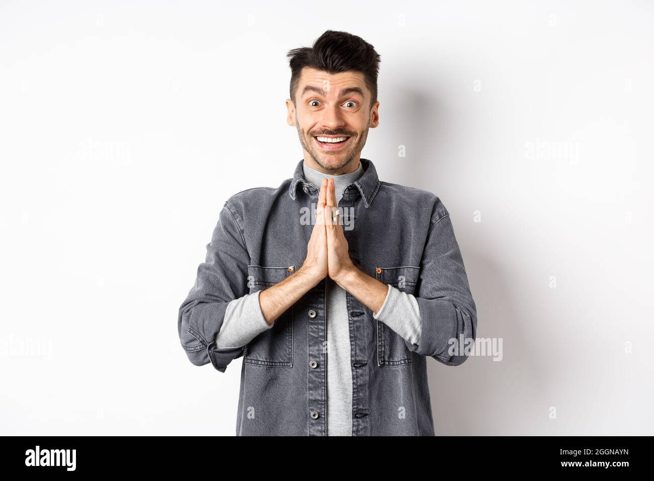 Per favore aiutami. Sorridente uomo carino che tiene le mani in gesto  namaste, chiedendo favore, dicendo grazie, guardando speranzoso ed eccitato  alla macchina fotografica Foto stock - Alamy