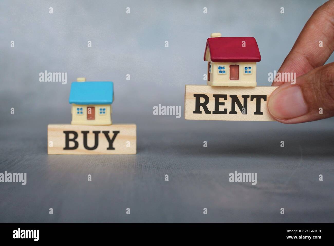 Concetto di immobile, immobile, acquisto e affitto. Immagine fuoco selettivo di mano scegliere cubo di legno e casa in miniatura con affitto testo Foto Stock