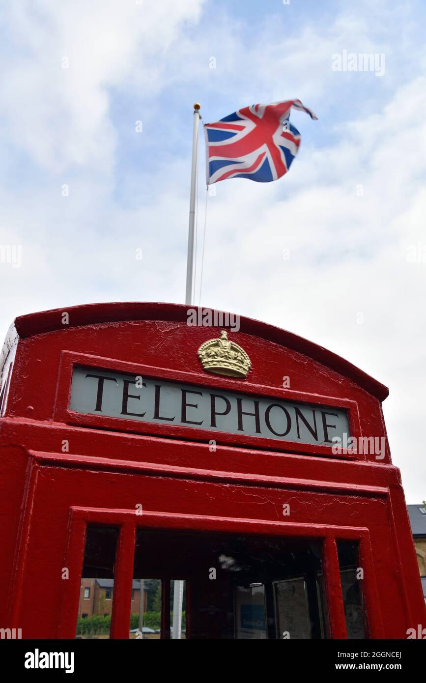 Telefono tradizionale britannico e bandiera Union Jack sulla stazione ferroviaria di Alresford, Alresford, Hampshire, Regno Unito. Foto Stock