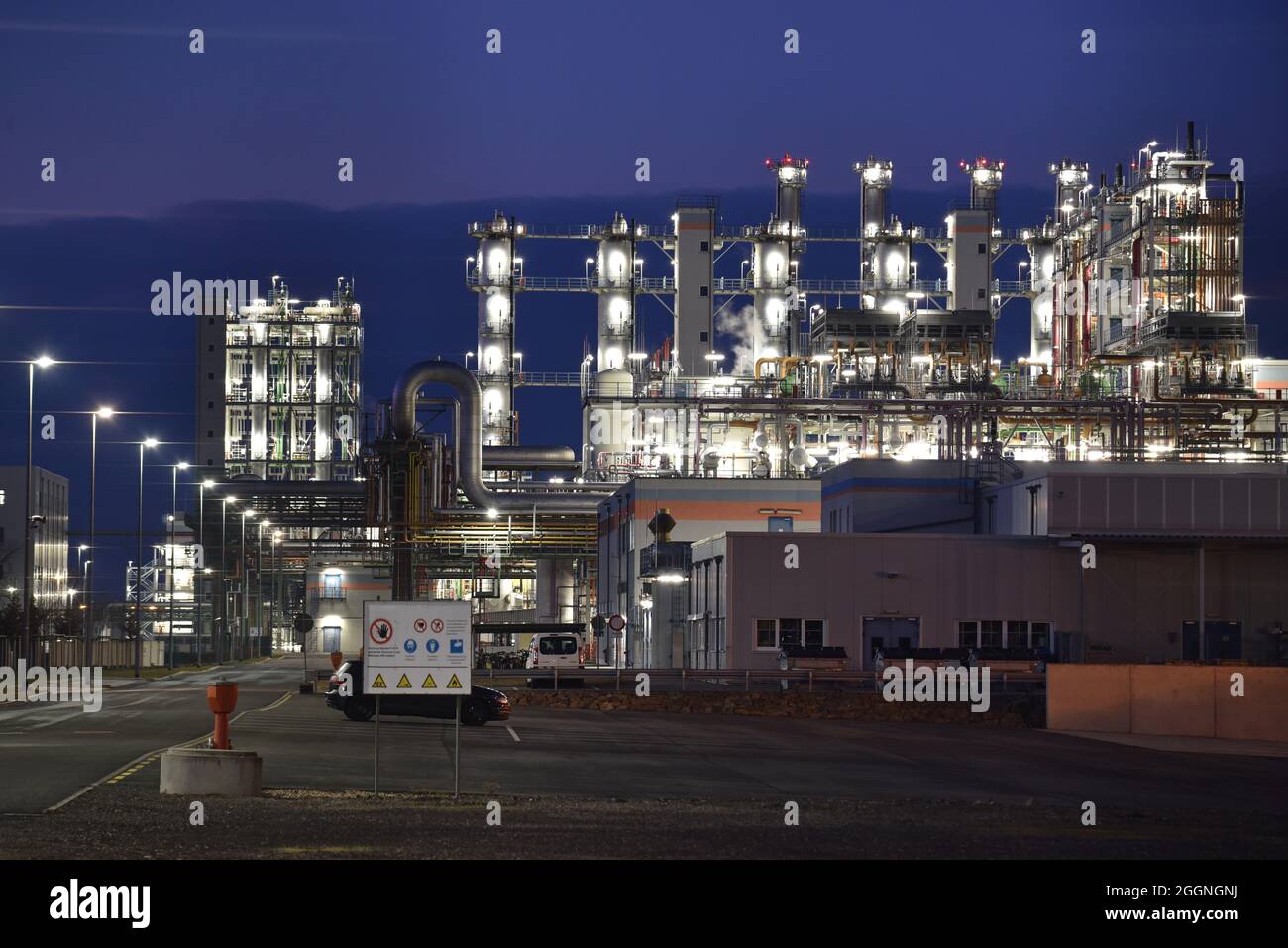 fabbrica chimica di notte con edifici, tubazioni e illuminazione - impianto industriale Foto Stock
