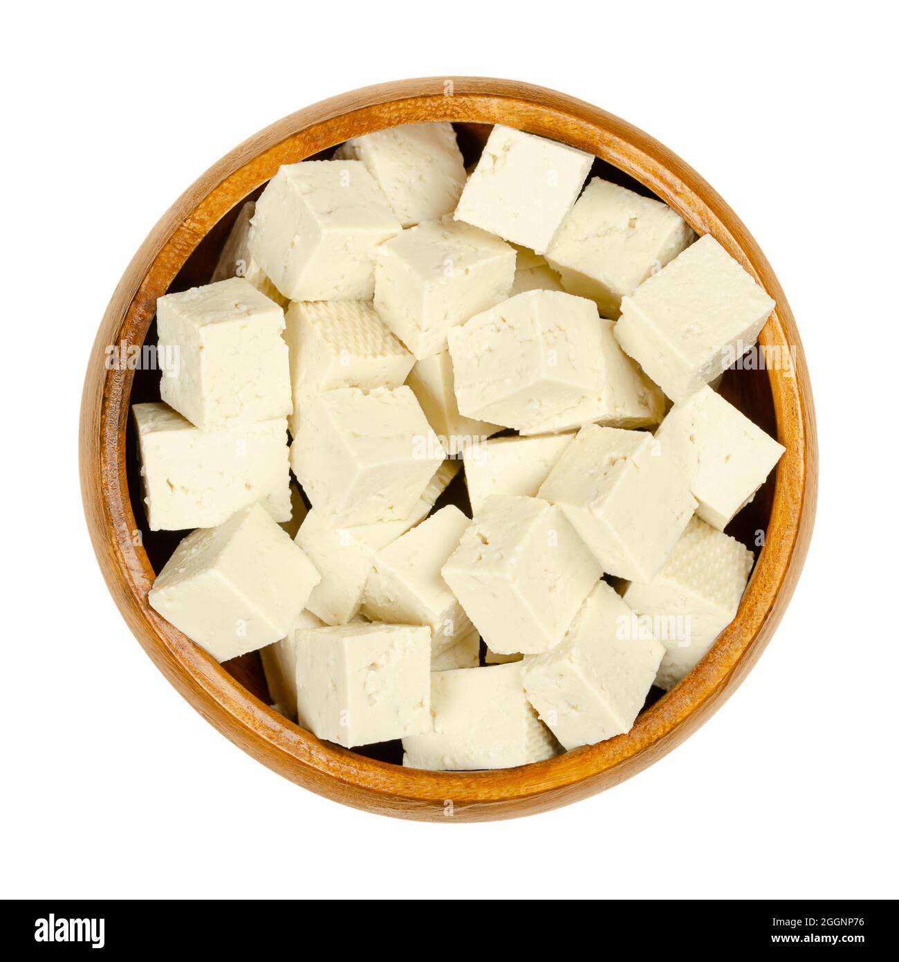 Cubetti di tofu bianco, in una ciotola di legno. Cagliata di fagioli a dadini, latte di soia coagulato, pressata in blocchi bianchi di diversa morbidezza. Foto Stock