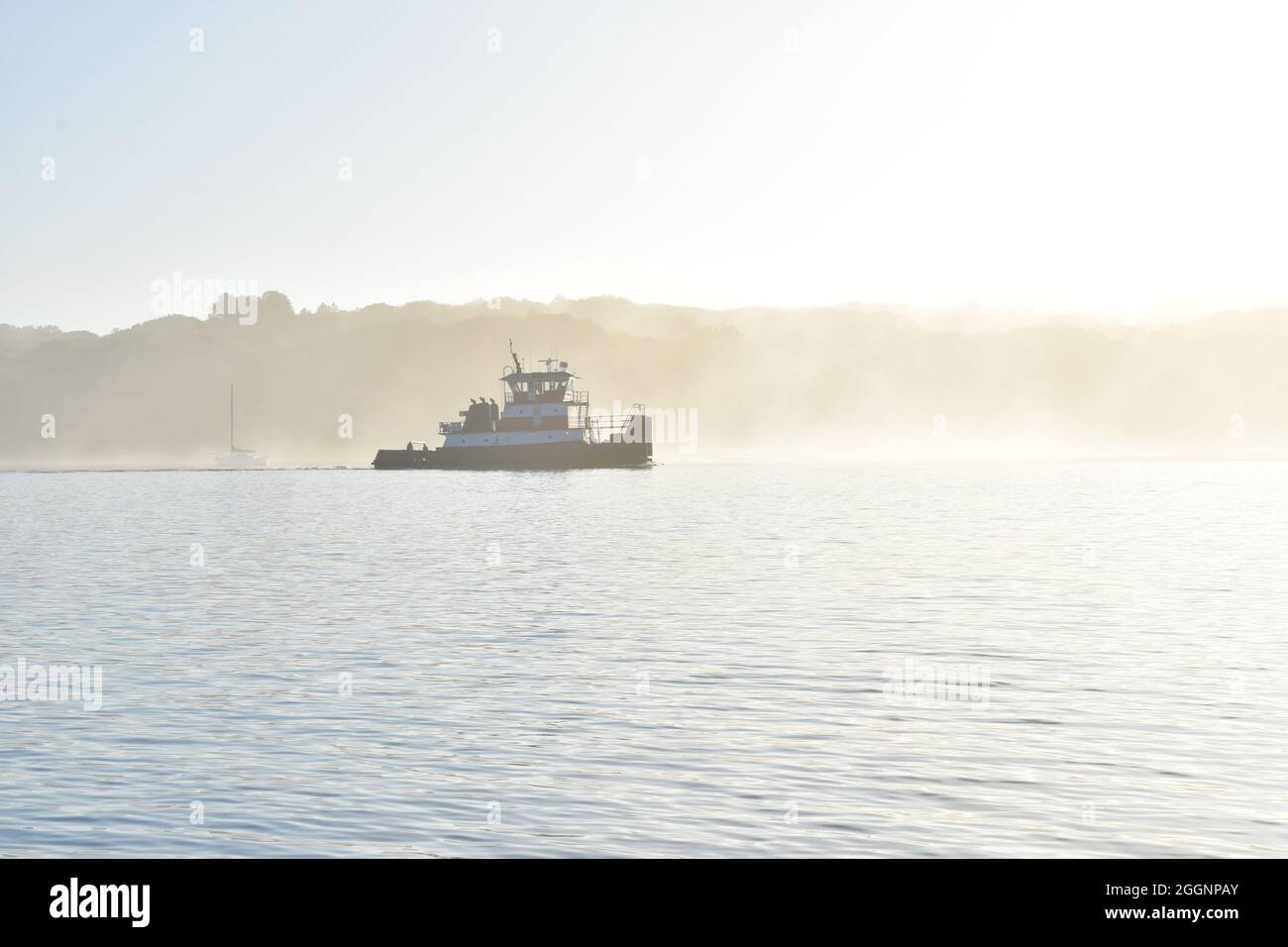 Tugboat retroilluminato nella nebbia mattutina estiva. Spazio di copia. Long Island, New York. Foto Stock
