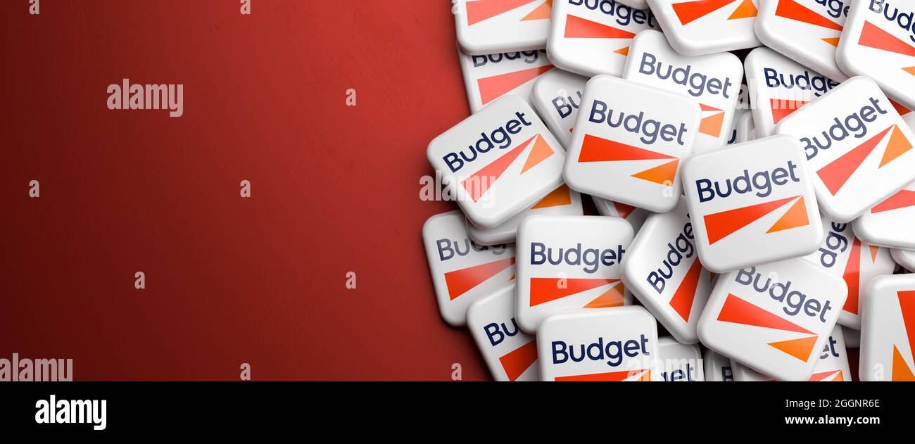 Logo della società di noleggio auto Budget su un mucchio su un tavolo. Spazio di copia. Formato banner Web. Foto Stock