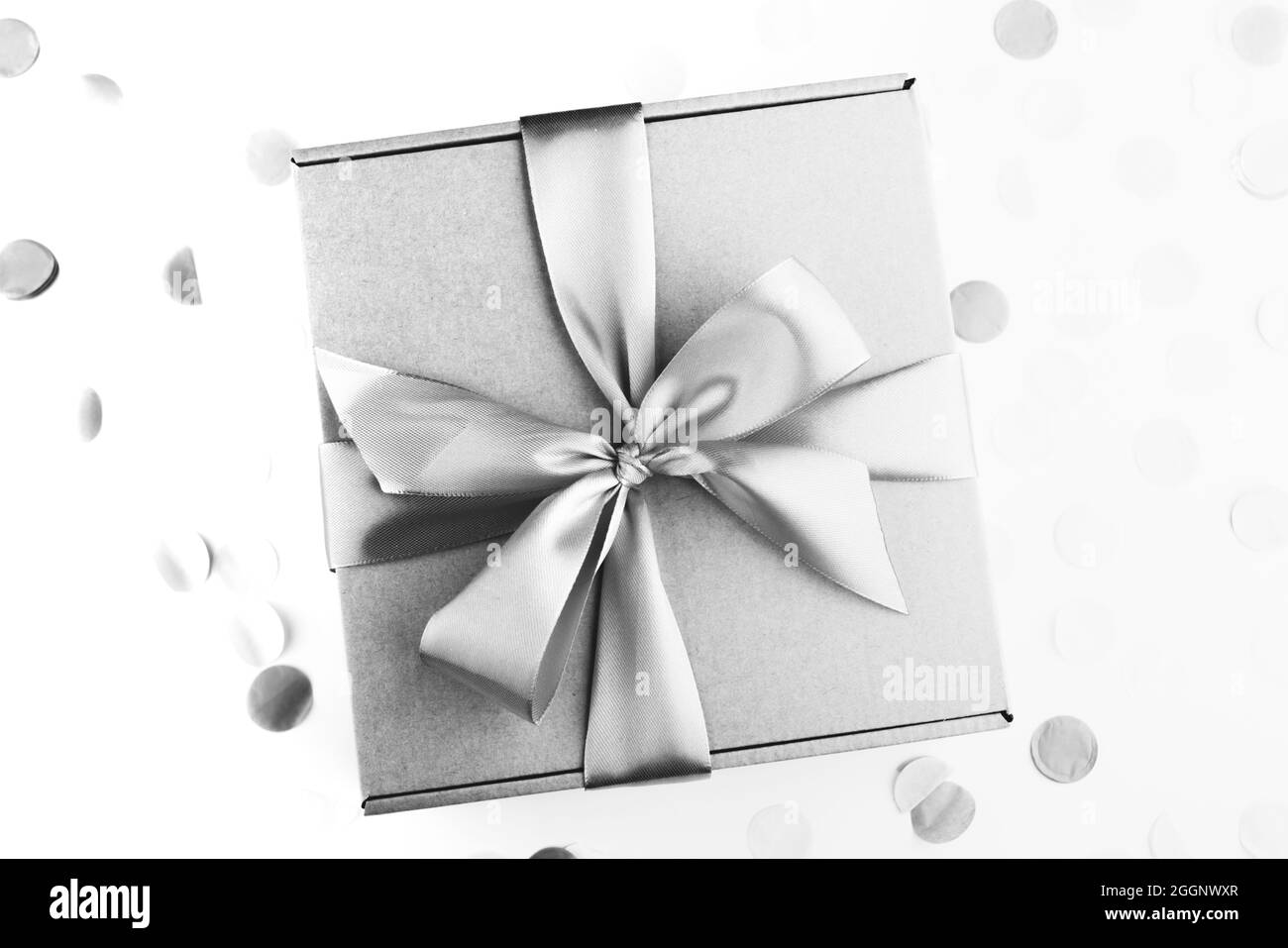 regalo con fiocco con confetti natalizi. Compleanno, sarchiatura, natale e concetto di congratulazioni. Stile a disposizione piatta. Monocromatico Foto Stock