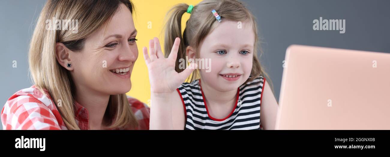 Madre e bambina sono seduti davanti al computer portatile e ondeggiando Foto Stock