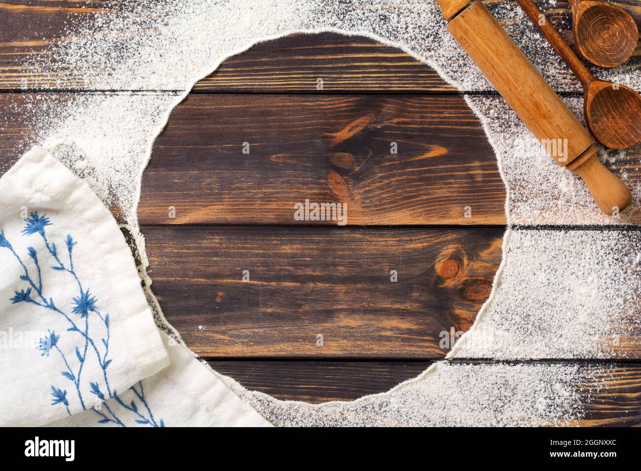Farina sparsa sotto forma di cerchio, tondino e tovagliolo di lino bianco su un vecchio sfondo di legno. Posiziona per il testo. Sfondo per la cottura Foto Stock