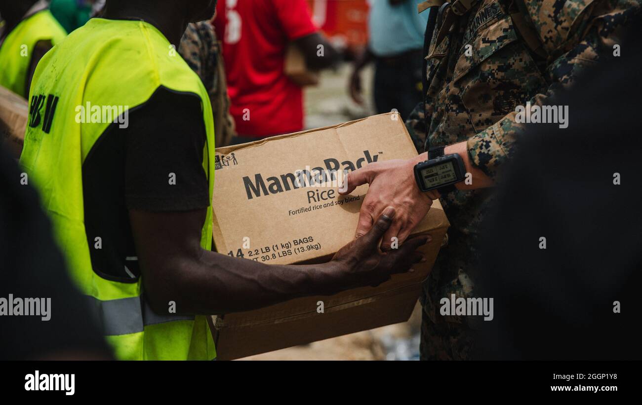 Una Marina statunitense con Joint Task Force-Haiti (JTF-Haiti) e un aiuto volontario scaricano le scatole per la ridistribuzione nel porto di Jeremie, Haiti, 31 agosto 2021. I Marines e i marinai a bordo della USS Arlington (LPD 24) hanno lavorato a sostegno della JTF-Haiti per una missione di assistenza umanitaria e di soccorso in caso di calamità. (STATI UNITI Foto del corpo marino di Lance CPL. Jacqueline C. Arre) Foto Stock