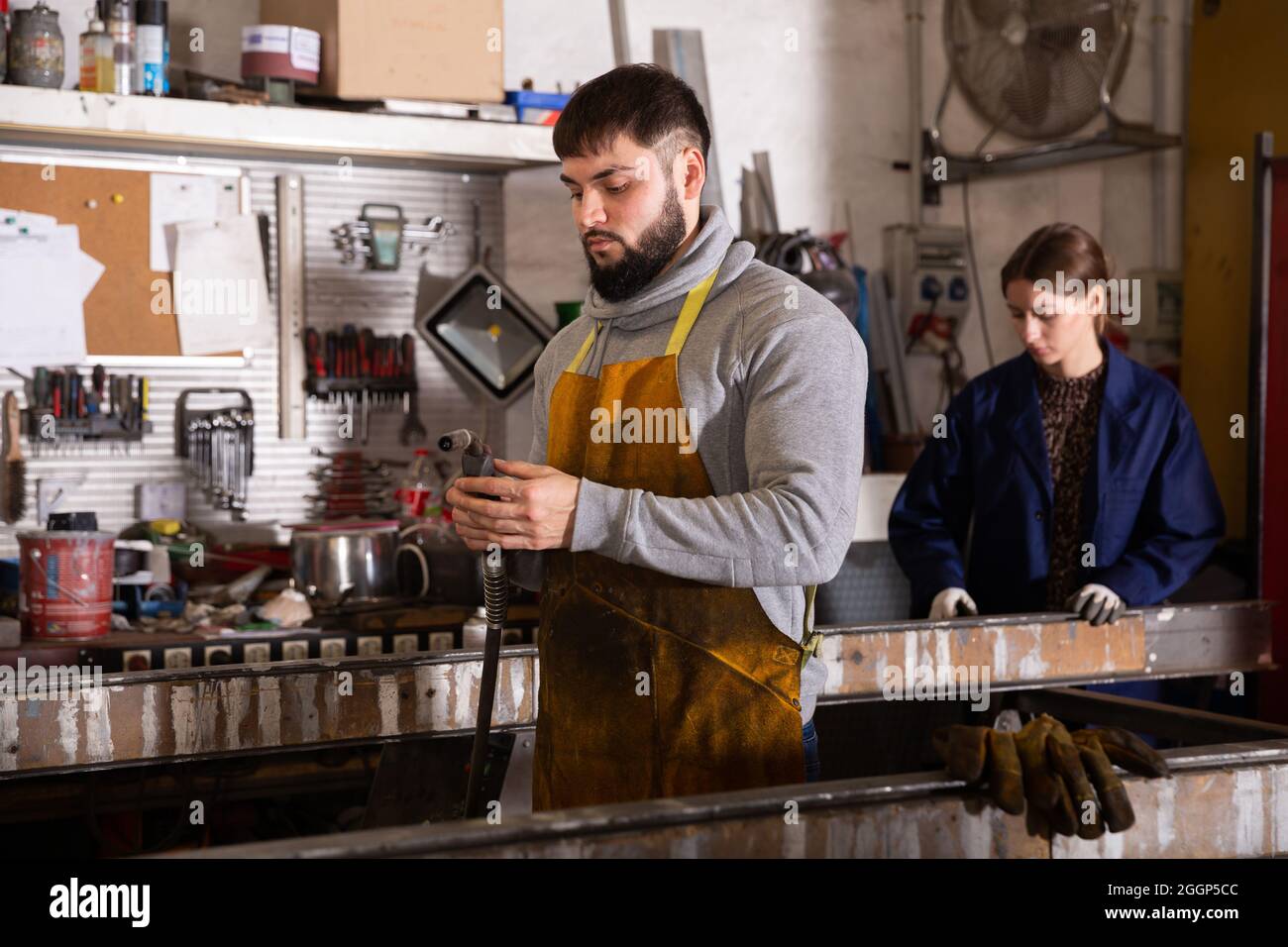 Giovane lavoratore durante il processo di lavoro in officina Foto Stock