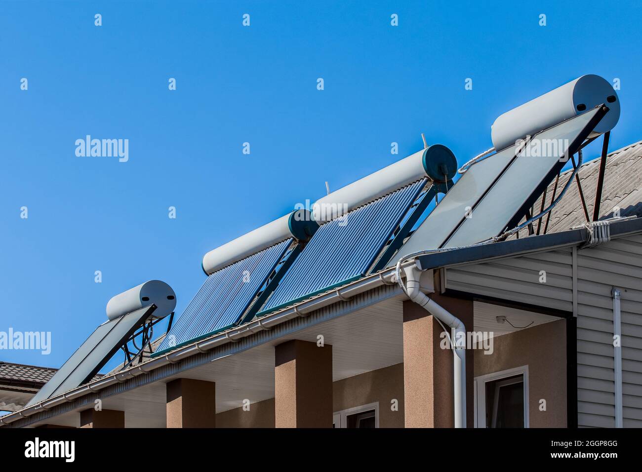 Caldaia termica e pannelli solari fonti di energia alternativa sul tetto della casa sullo sfondo del cielo blu. Foto Stock