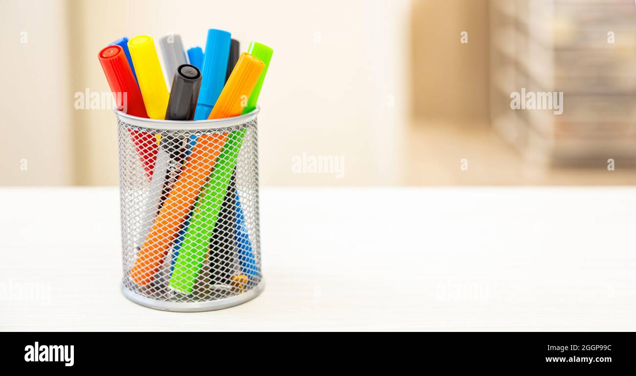 Pennarelli colorati posti in un supporto sulla scrivania dello studente, sfocatura dello sfondo interno della stanza. Istruzione, ritorno a scuola, concetto di creatività dei bambini. Spazio copia, templ Foto Stock