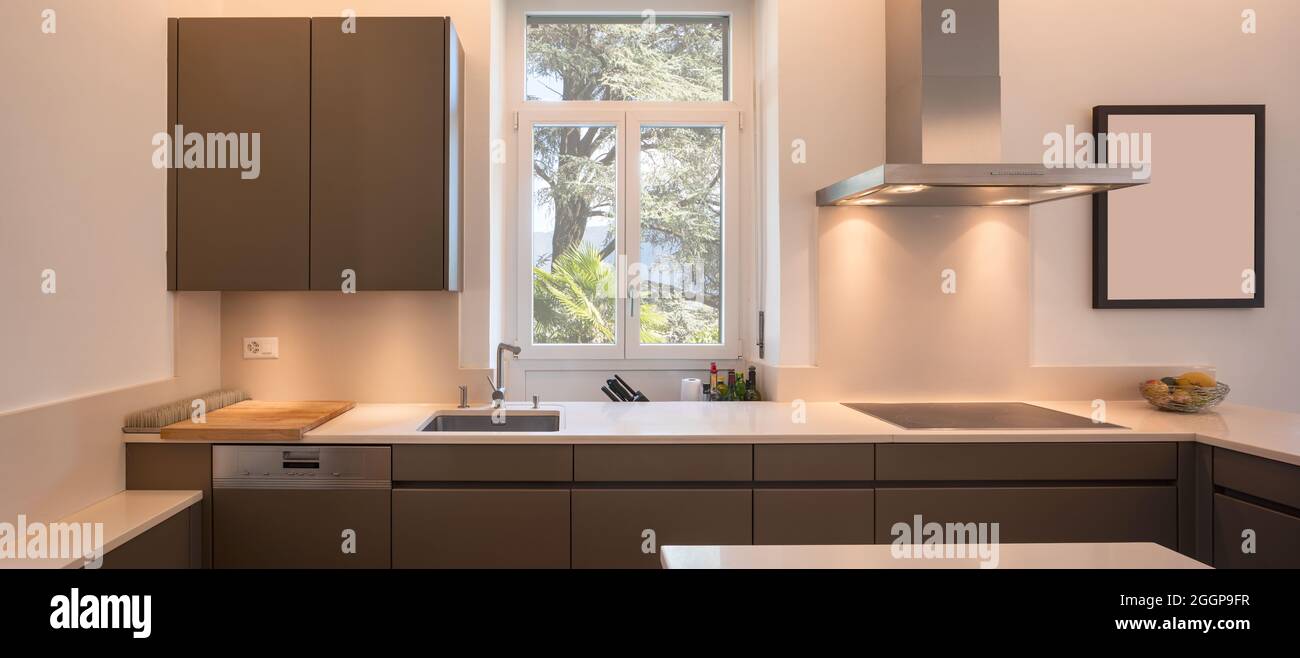 Moderna cucina in una villa d'epoca con finestra e parquet. Banconi bianchi e porte marroni. Nessuno dentro Foto Stock