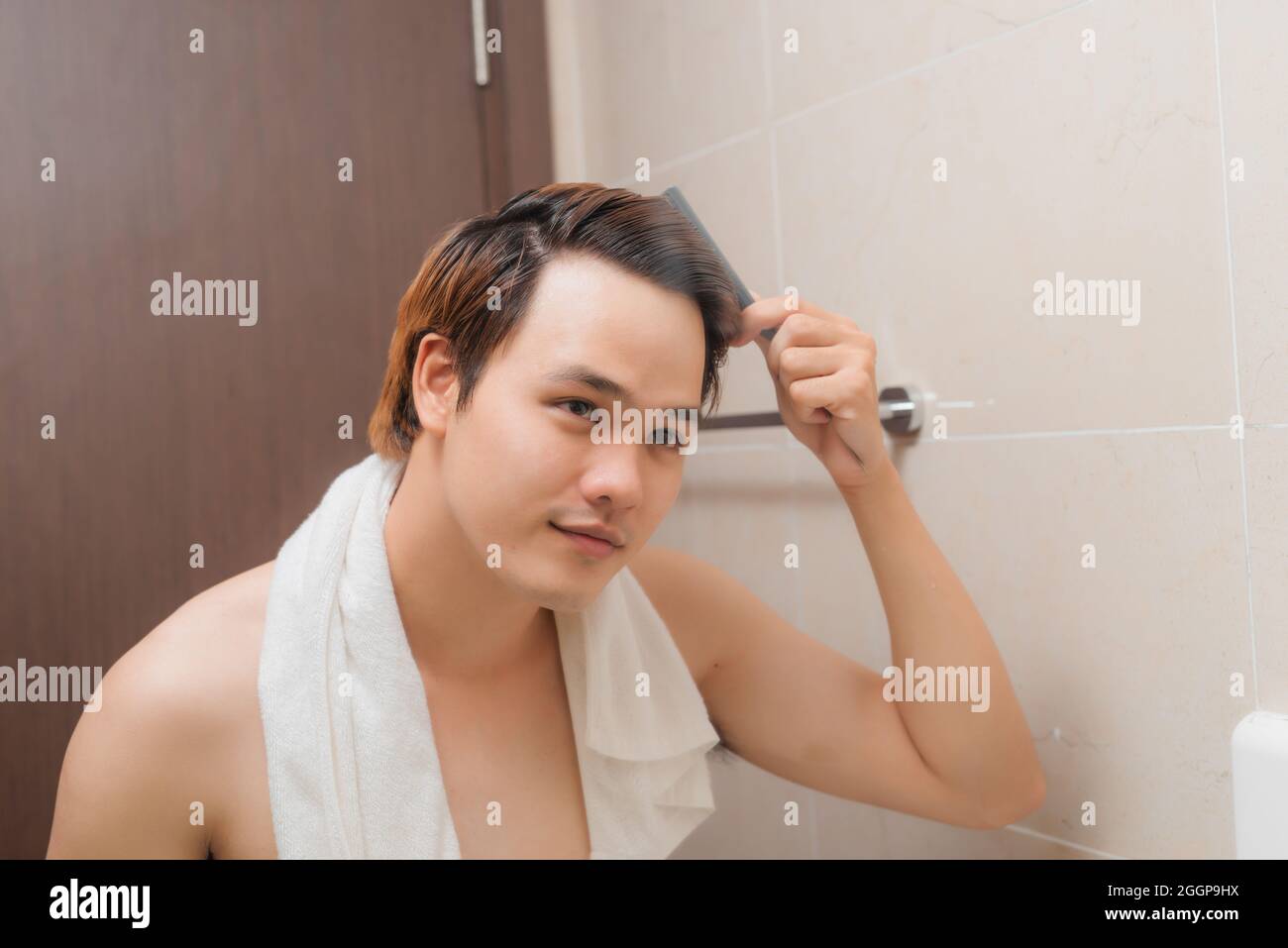 Riflesso dei capelli di boccola dell'uomo giovane nello specchio Foto Stock