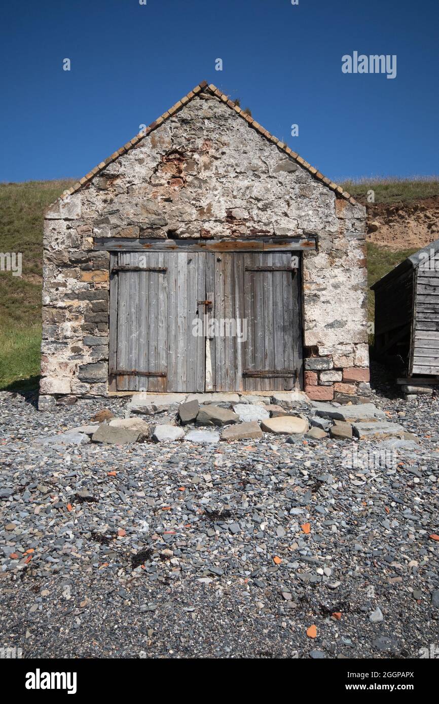 Capannone di deposito intemperato / casa di barca su una spiaggia di ghiaia a Holy Island, Northumberland; Inghilterra. Foto Stock