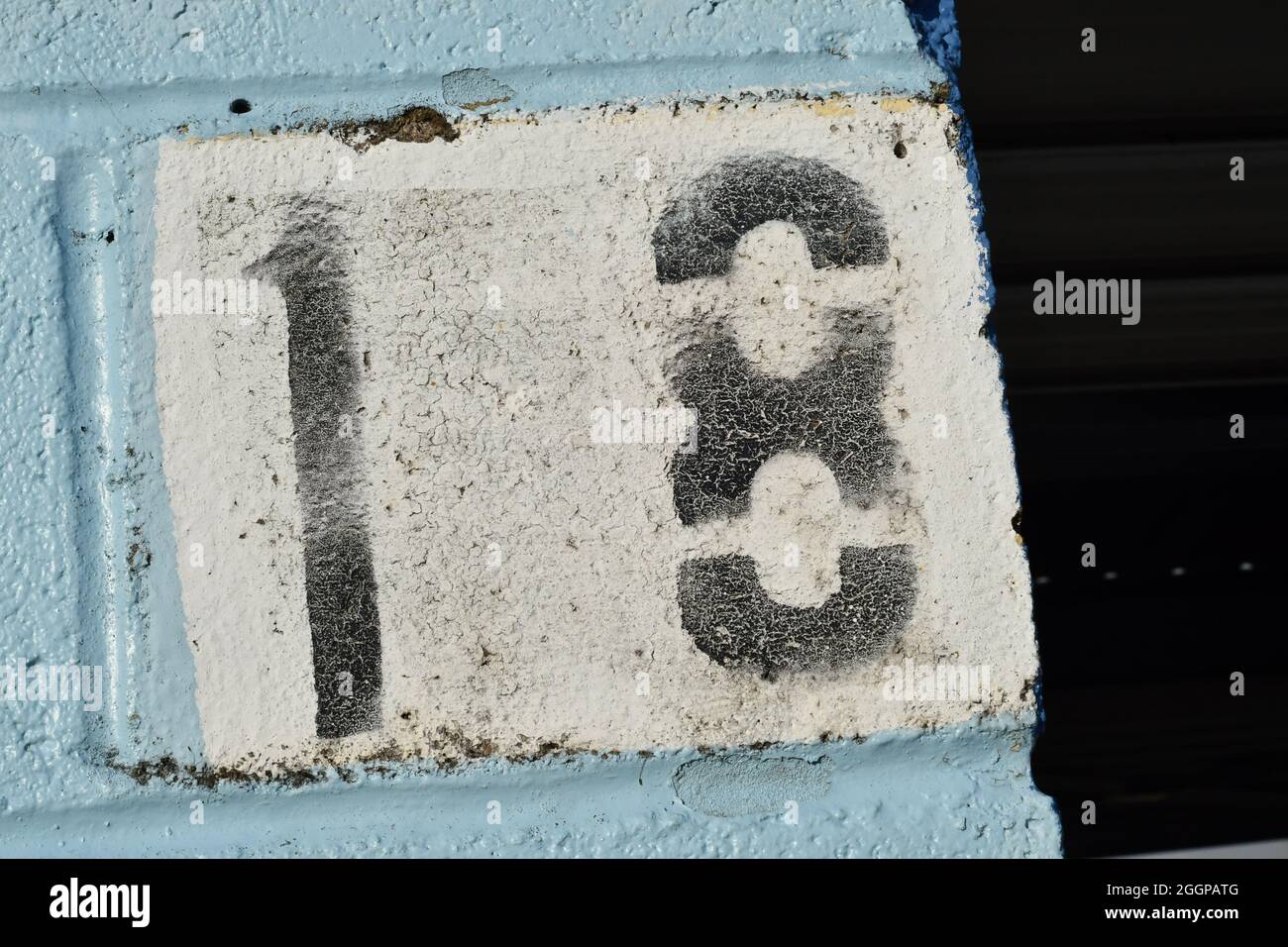 Un numero stenciled diciotto in nero su uno sfondo bianco circondato da blu su un blocco di cemento Foto Stock