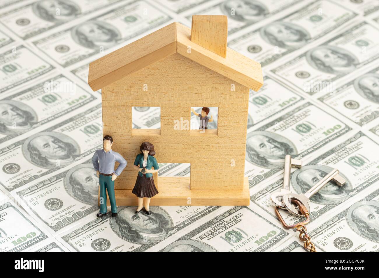 Investire in un concetto di casa. Prezzi immobiliari. Casa giocattolo e figurina coppia su sfondo banconota da dollaro Foto Stock