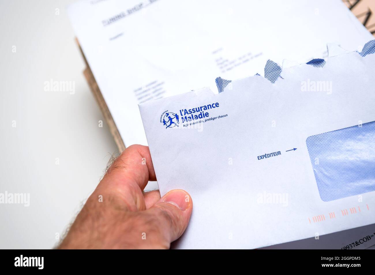 Busta aperta con mano di Assurance Maladie tradotta in francese Assicurazione sanitaria Foto Stock