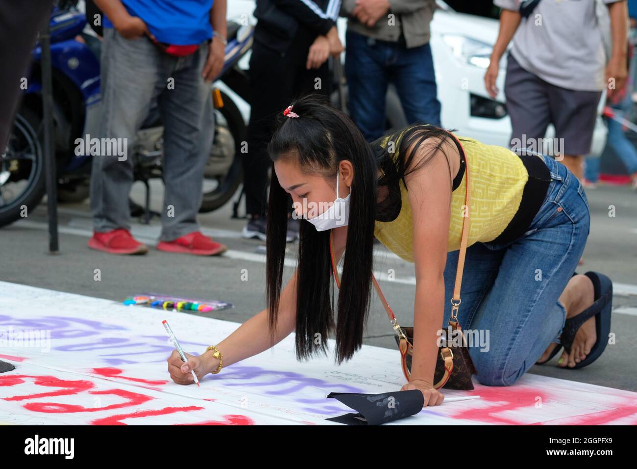 Bangkok (Thailandia), 2 settembre 2021, una protesta femminile contribuisce a una bandiera di protesta che chiede le dimissioni del primo Ministro generale tailandese Prayut Chan-ocha. La protesta ha chiuso le carreggiate nord-sud dell'incrocio di Asoke Road nel centro di Bangkok e ha limitato il traffico lungo Sukhumvit Road. L'evento di oggi è stato parte di una serie di proteste in corso in tutto il paese per esprimere disaffezione con le prestazioni del governo attuale durante la pandemia di COVID. Foto Stock Bangkok (Thailandia), 2 settembre 2021, una protesta femminile contribuisce a una bandiera di protesta che chiede le dimissioni del primo Ministro generale tailandese Prayut Chan-ocha. La protesta ha chiuso le carreggiate nord-sud dell'incrocio di Asoke Road nel centro di Bangkok e ha limitato il traffico lungo Sukhumvit Road. L'evento di oggi è stato parte di una serie di proteste in corso in tutto il paese per esprimere disaffezione con le prestazioni del governo attuale durante la pandemia di COVID. Foto Stock