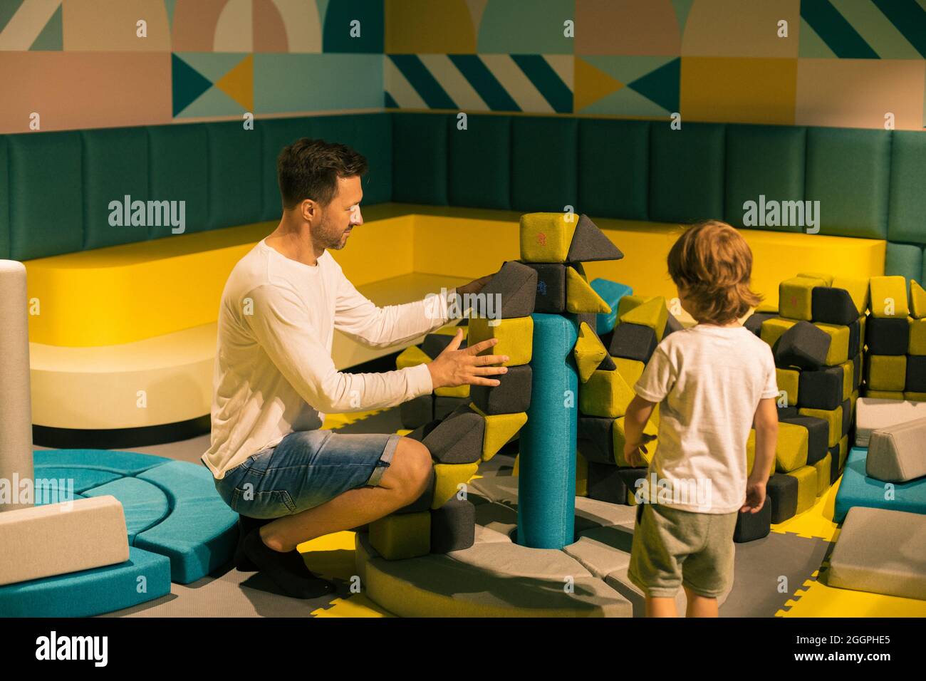 Papà e figlio stanno costruendo un castello dalle morbide forme colorate nel centro per bambini. Lezioni e giochi educativi. Attività ricreative e di intrattenimento. Gioco e de Foto Stock