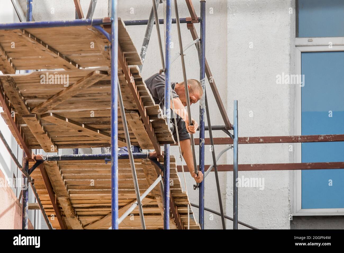 Bielorussia, Bobruisk - 21 agosto 2020: Uomo adulto lavoratore industriale su ponteggio vicino a un edificio cittadino, attrezzature di lavoro di sicurezza. Foto Stock