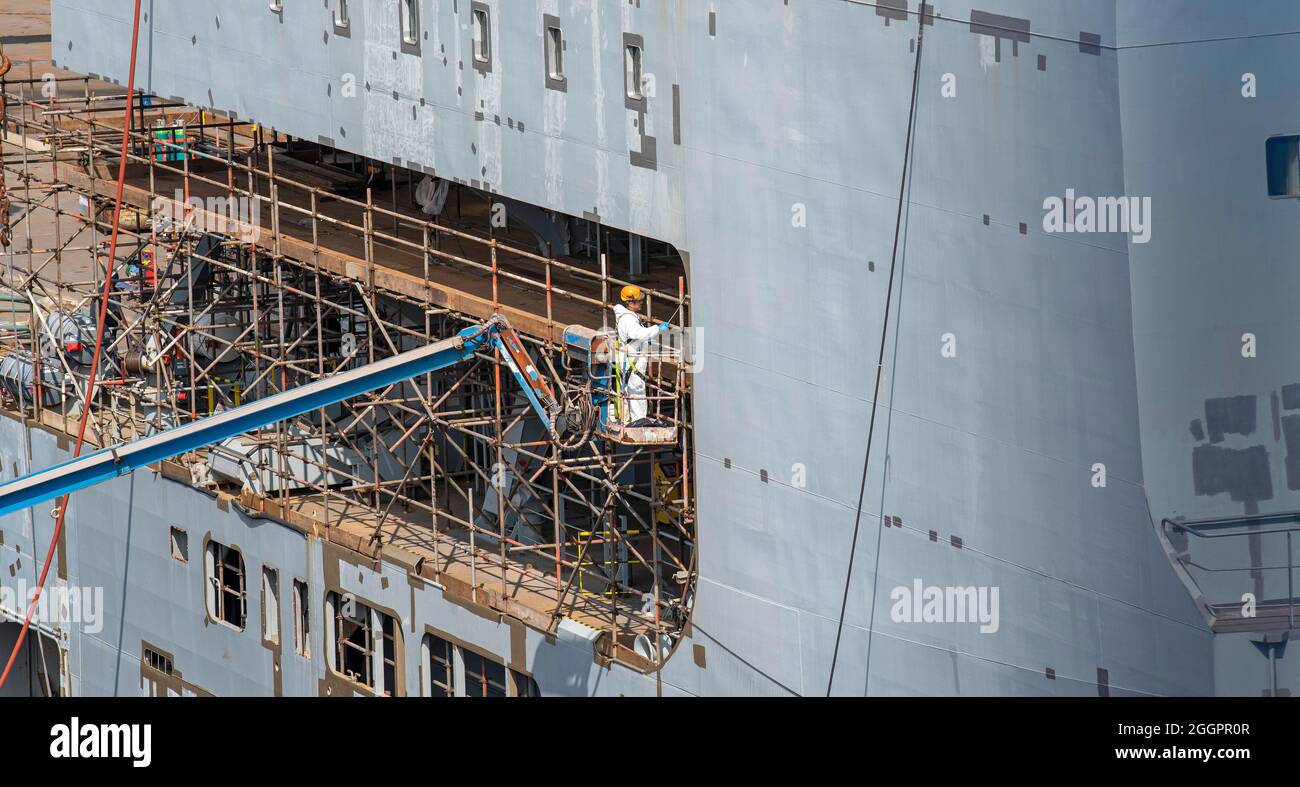 Falmouth, Cornovaglia, Inghilterra, Regno Unito. 2021. Nave RFA Cardigan Bay in bacino asciutto in fase di rimontaggio. Appaltatori che dipingendo la nave. Foto Stock