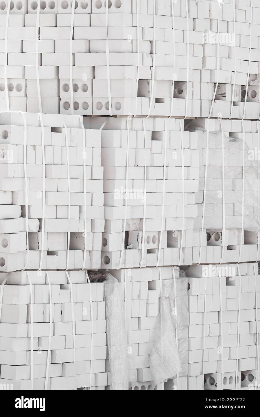 Il materiale dei blocchi bianchi in mattoni silicati viene imballato e conservato all'aperto in un sito industriale. Foto Stock