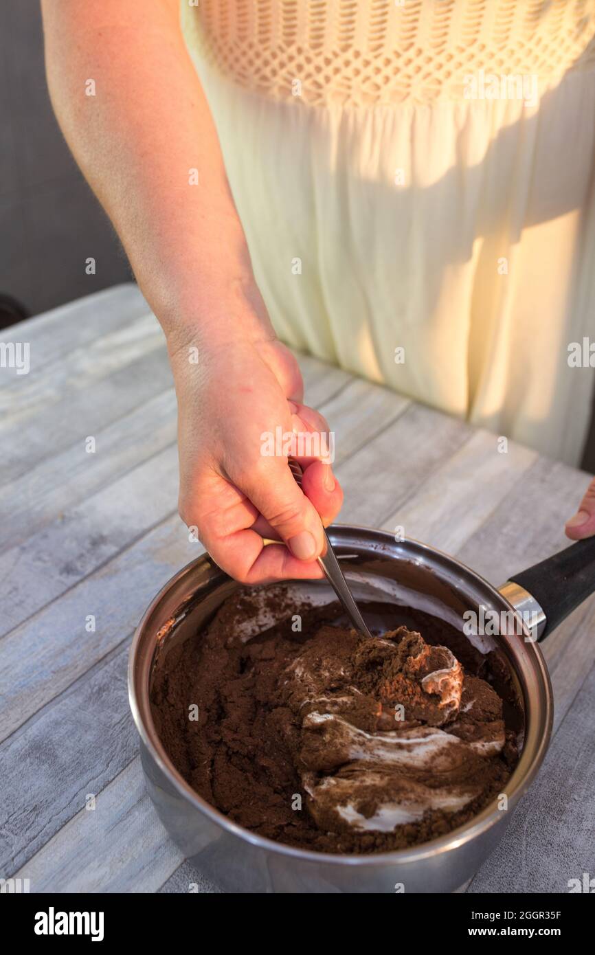 Il processo di preparazione dello smalto al cioccolato. Passo dopo passo. Gli ingredienti vengono mescolati in una pentola. Riscaldare lentamente per dissolversi. Foto Stock