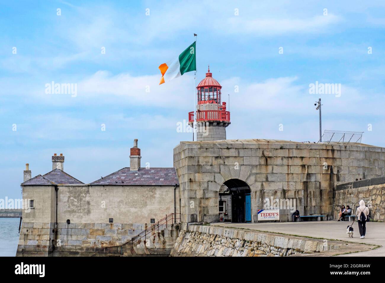 Il faro sul Molo Est a Dun Laoghaire, Dublino, Irlanda con la bandiera della Repubblica d'Irlanda a pieno albero in testa. Faro costruito nel 1847. Foto Stock