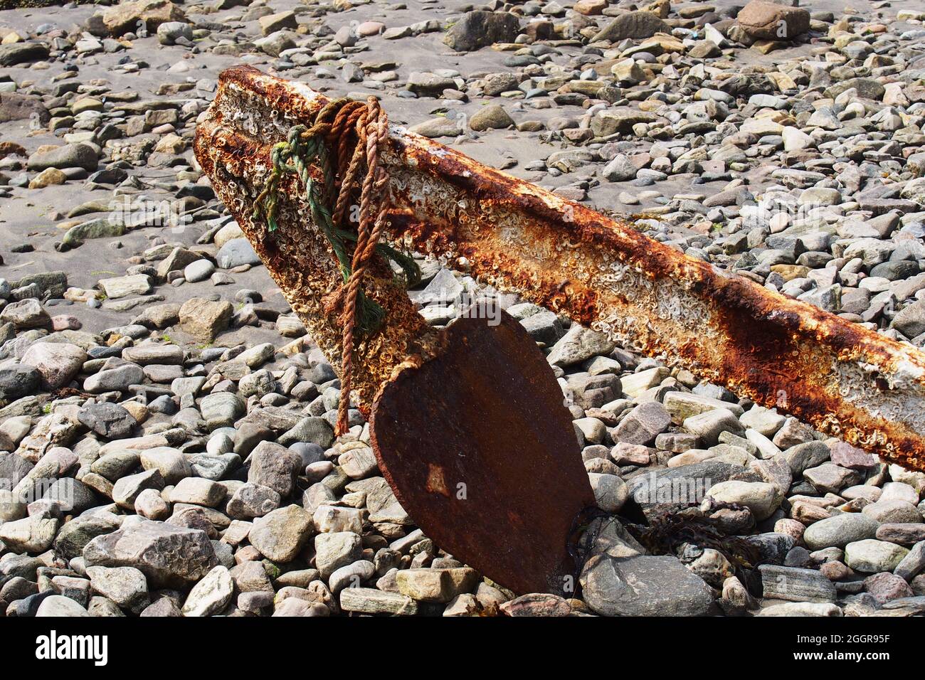 Un'immagine di una vecchia, arrugginita, spade ancora che è stato abbandonato su una spiaggia stoney con la sua punta bloccata nelle pietre Foto Stock