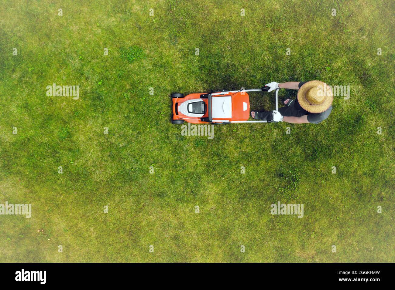 Un giovane uomo sta falciando un prato con un tosaerba. Foto Stock