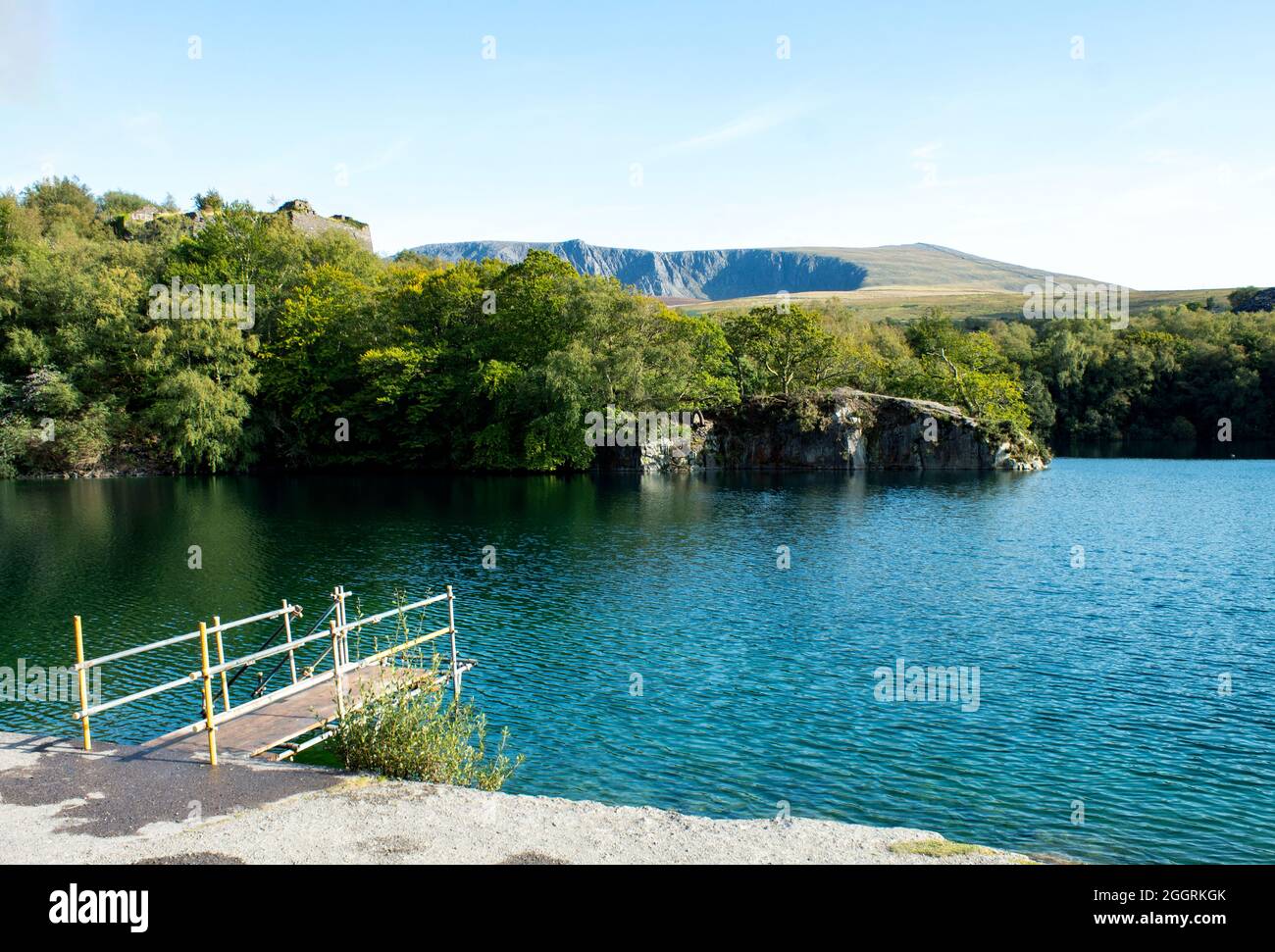 Bella cava di Dorothea, Snowdonia, Galles. Paesaggio tranquillo con foresta, lago e un piccolo molo in primo piano. Disusato allagato miniera di ardesia whic Foto Stock