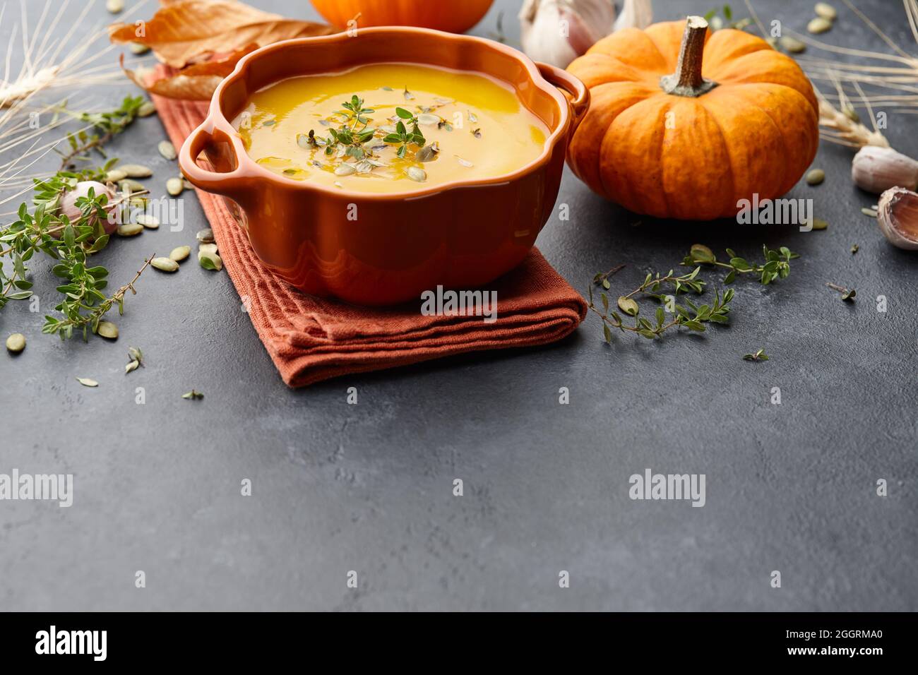 Zuppa di zucca con timo e semi di zucca su sfondo nero Foto Stock