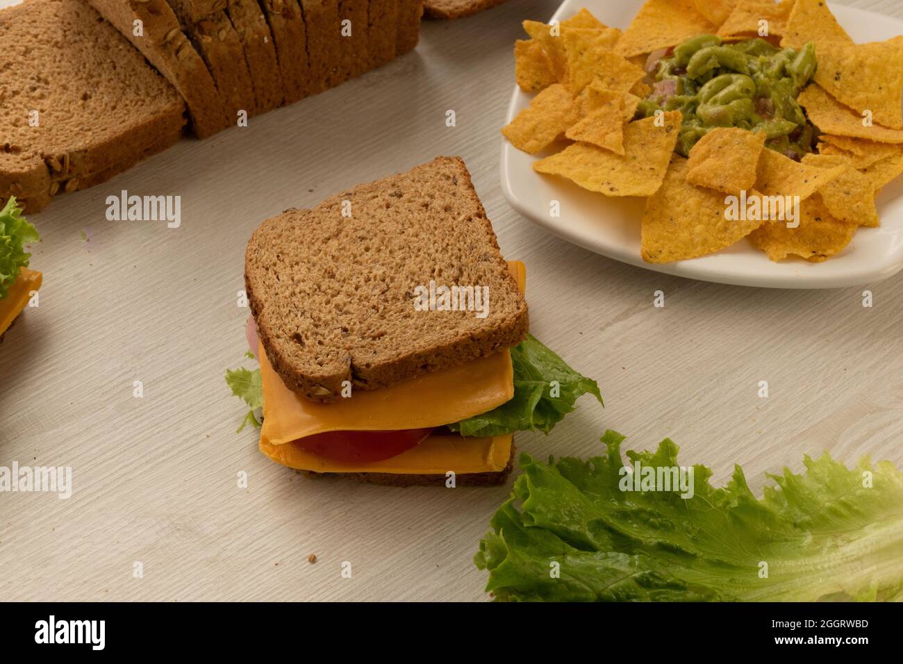 dettagli di sandwich preparati con ingredienti freschi, armati di pane integrale di grano, formaggio, lattuga e un piatto con nachos su un tavolo, delizioso Foto Stock