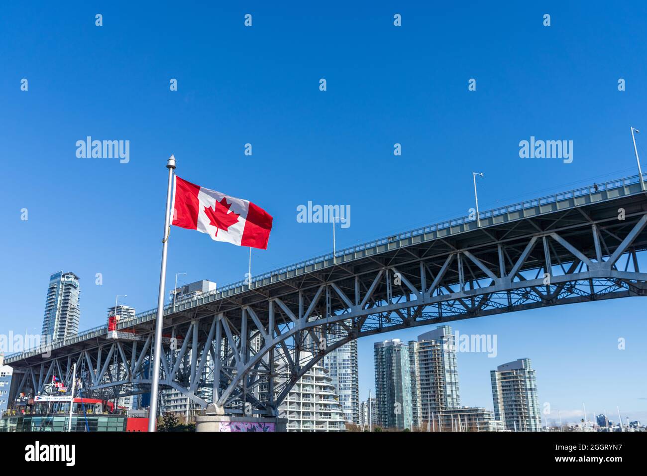 Bandiere nazionali del Canada e Granville Bridge. Skyline dei grattacieli di Vancouver in background. Concetto di vita urbana canadese. Foto Stock