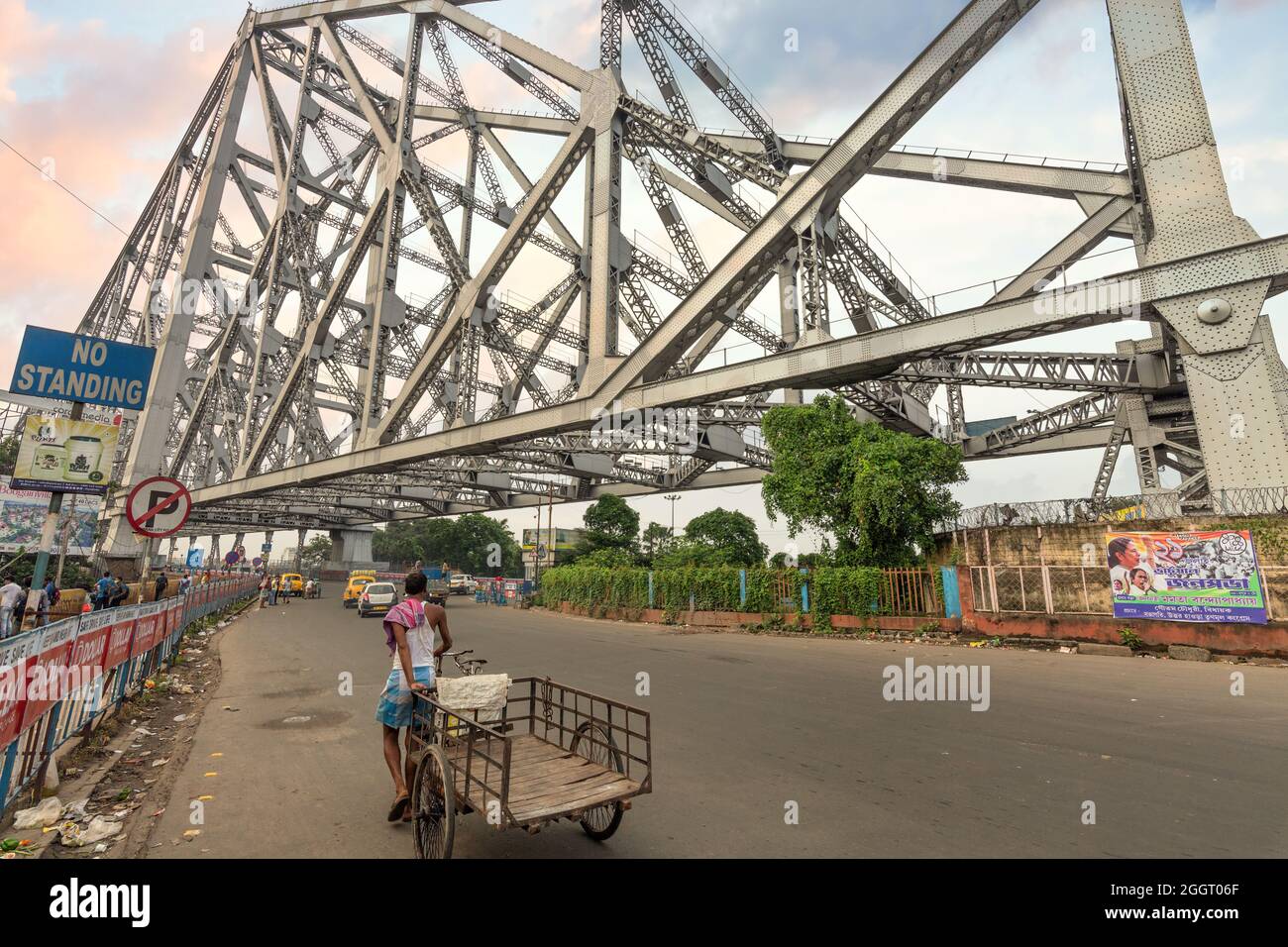 Traffico cittadino sul ponte Howrah con vista dei mezzi di trasporto pubblico e dei pendolari a Kolkata all'alba Foto Stock