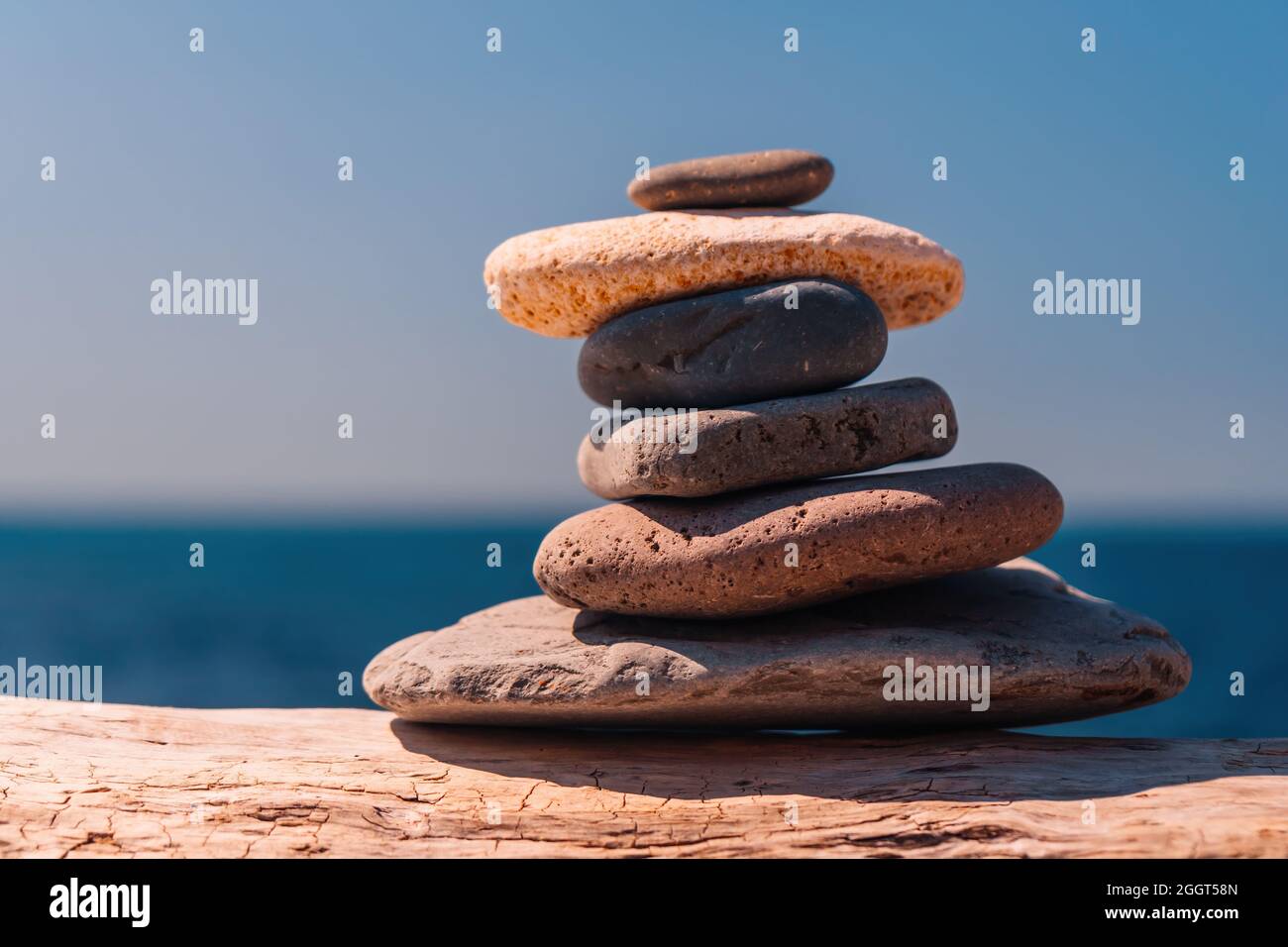 Equilibrata piramide di ciottoli sulla spiaggia in una giornata di sole. Abstract Sea bokeh sullo sfondo. Messa a fuoco selettiva. Pietre Zen sulla spiaggia di mare, meditazione Foto Stock