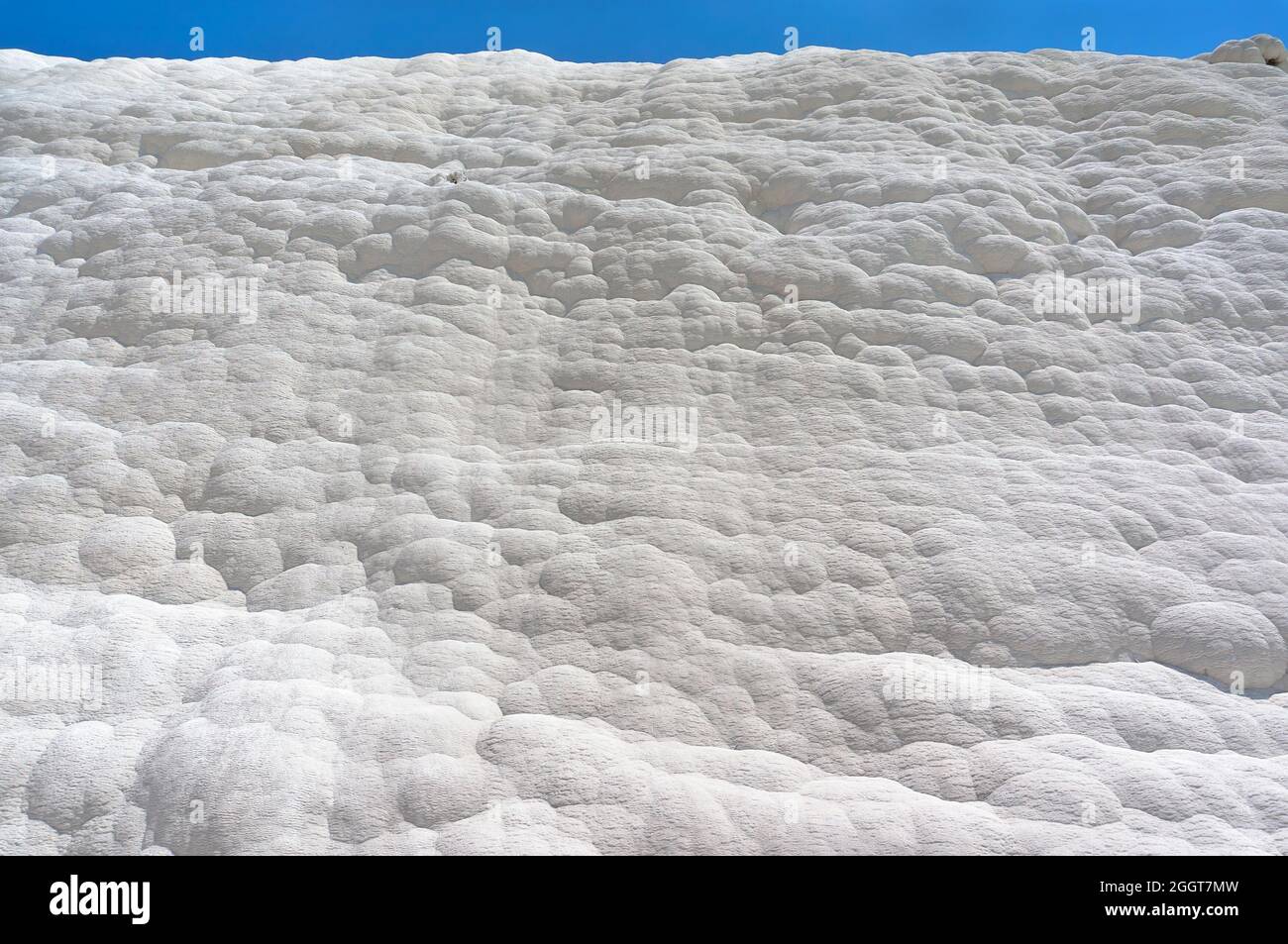 Pamukkale, castello di cotone, meraviglia naturale è creato da un strati di travertino bianco che assomiglia a cotone, Turchia. Parete naturale di pamukkale contro un blu Foto Stock