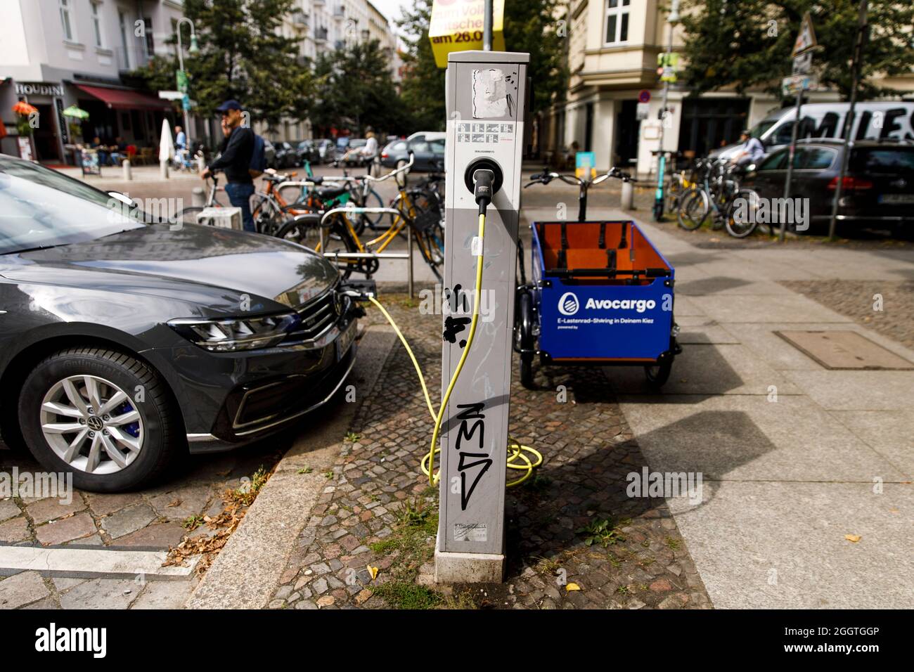 Berlino, Germania. 2 settembre 2021. Un'auto elettrica si trova in una stazione di ricarica in una zona residenziale nel quartiere di Prenzlauer Berg. Una e-bike (r) di Avocargo si trova di fronte ad essa. Credit: Carsten Koall/dpa/Alamy Live News Foto Stock