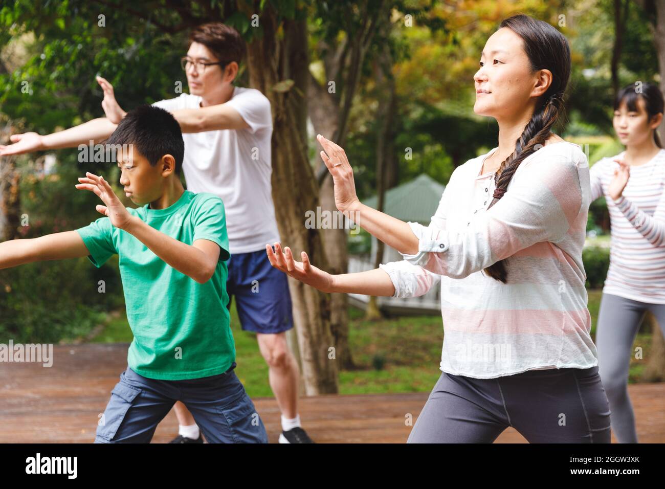 Genitori asiatici, figlio e figlia che si esercitano all'aperto, praticando tai chi Foto Stock